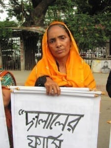 Bangladesh.Trafficking human chain._Selina Begum, 60, whose son is still missing, holding a placard saying hang trafficking traders.6.15.Mushfique Wadud