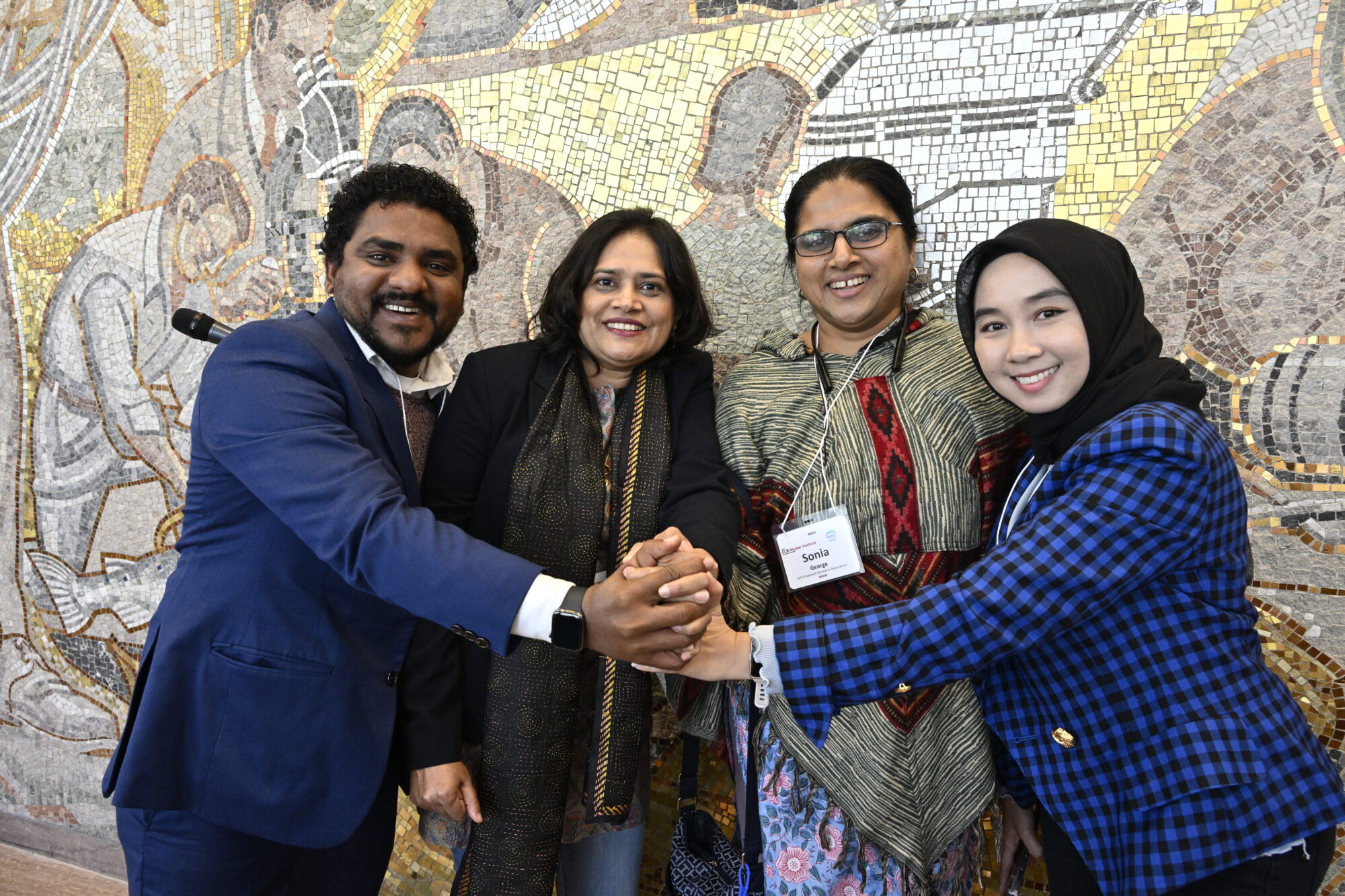 Four Global Labor Leadership Initiative (GLLI) participants clasp hands at AFL-CIO Washington, D.C., headquarters. Photo: Kaveh Sardari